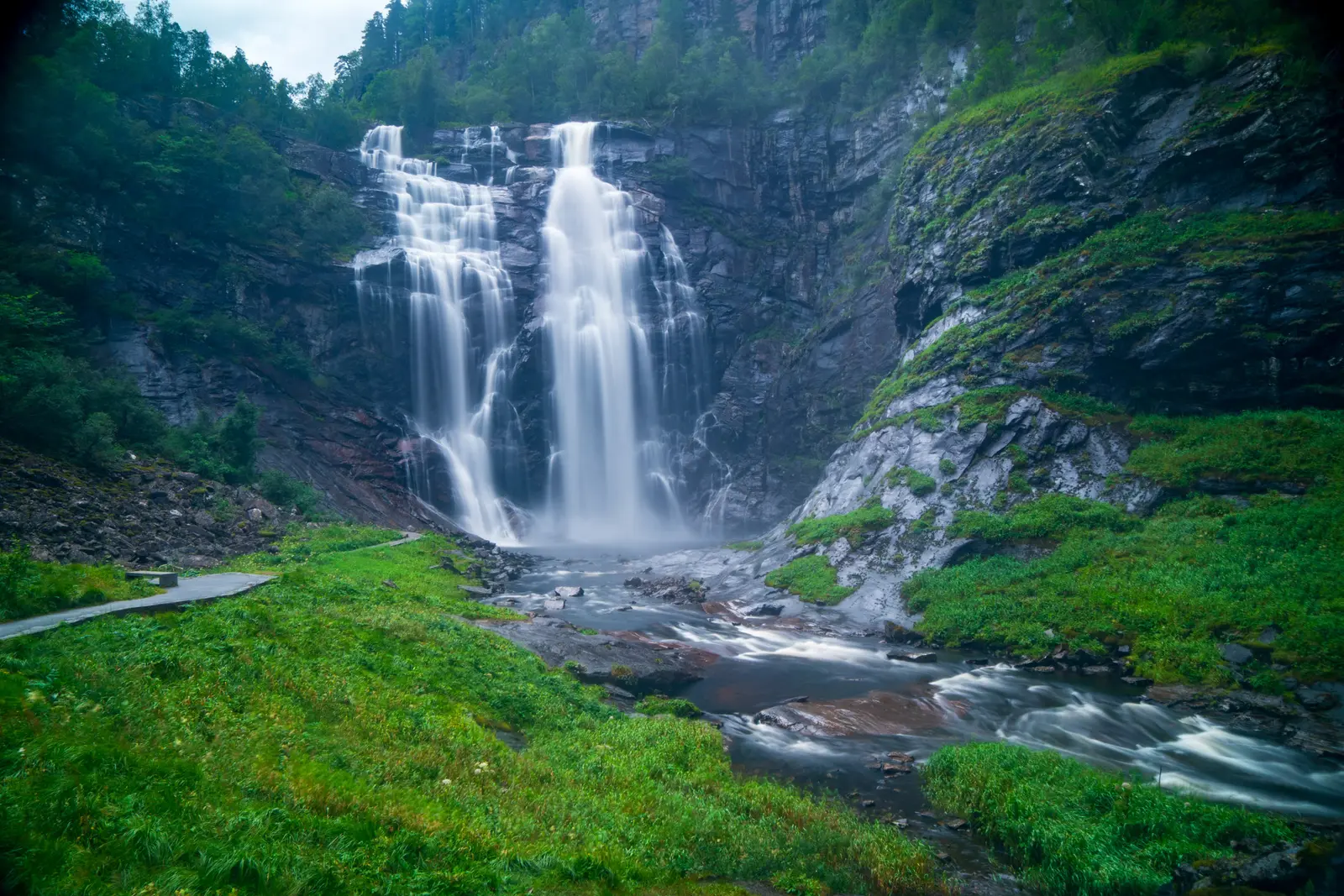 Breiter Wasserfall stürzt über eine bemooste Felswand.