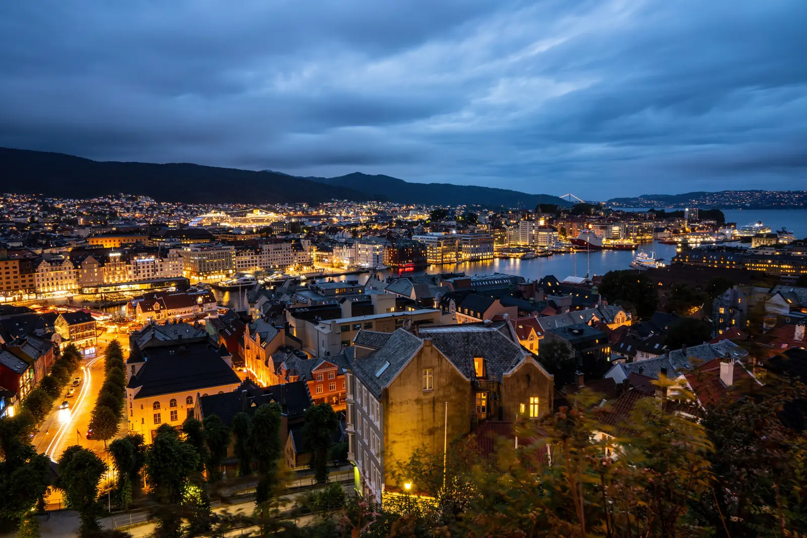 Stadt am Wasser in der blauen Stunde, warme Straßenbeleuchtung zwischen den Häusern.