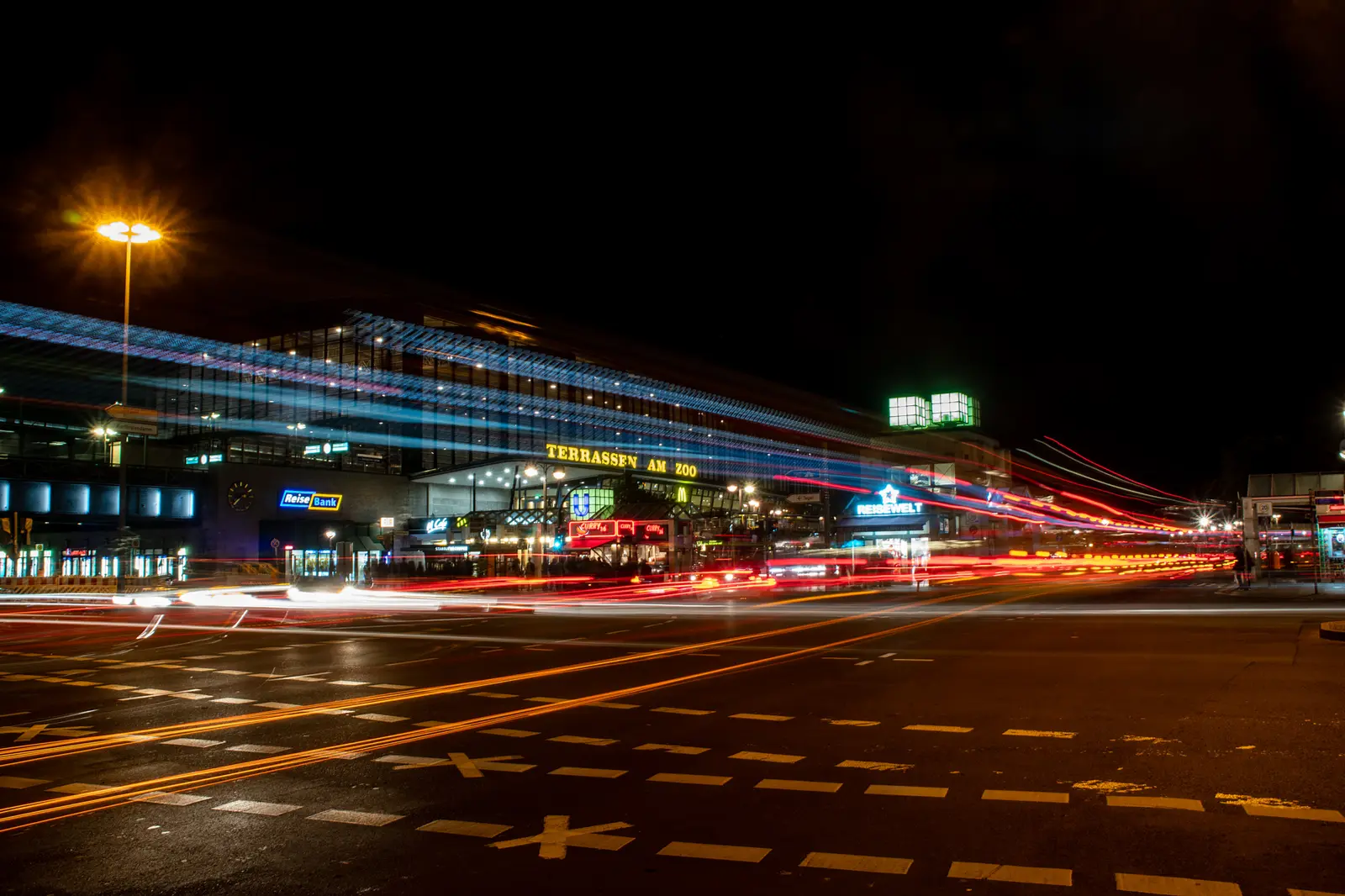 Kreuzung bei Nacht mit langen Lichtspuren des vorbeiziehenden Verkehrs.