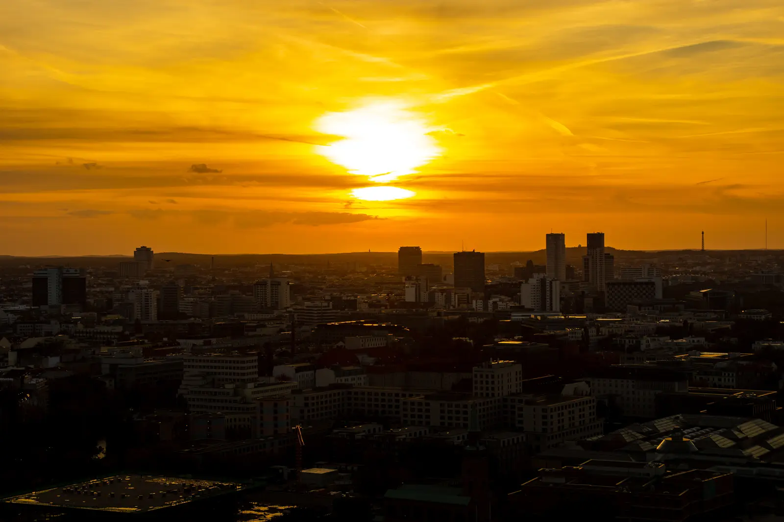 Tief stehende Sonne über der Stadtsilhouette, die Dächer bereits im Schatten.