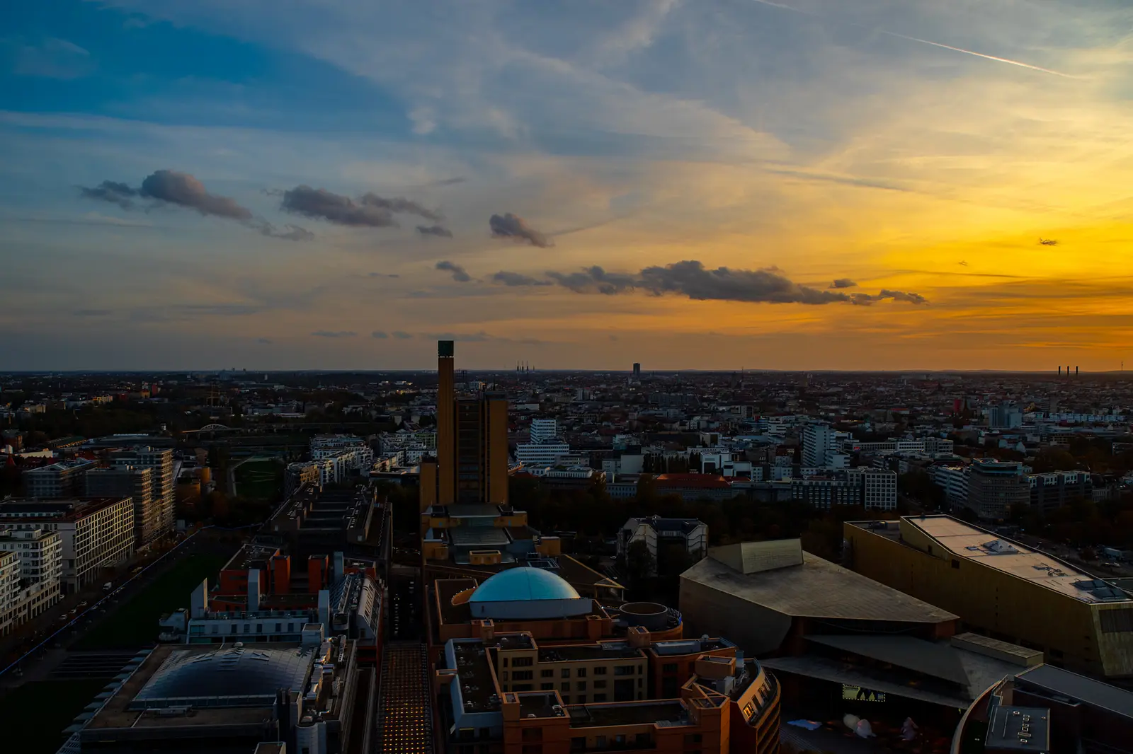 Blick über Dächer und Baustellen Richtung Horizont in der Abenddämmerung.